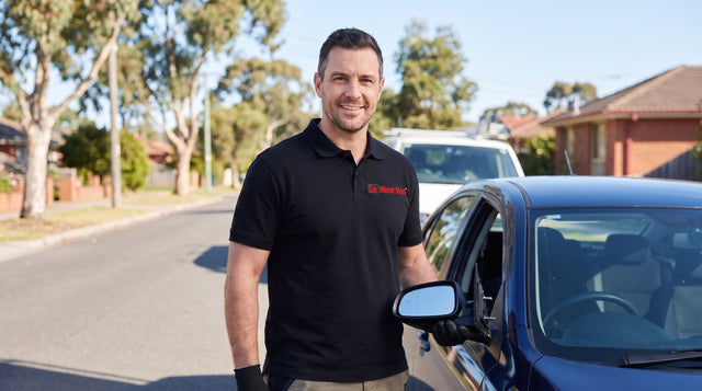 Car Mirror Man technician holding a replacement side mirror unit beside a car